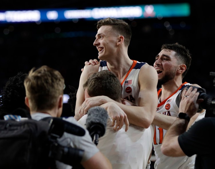 Virginia’s Kyle Guy is mobbed by teammates after his three foul shots with 0.6 seconds left gave the Cavaliers a 63-62 win over Auburn in the Final Four on Saturday in Minneapolis. 