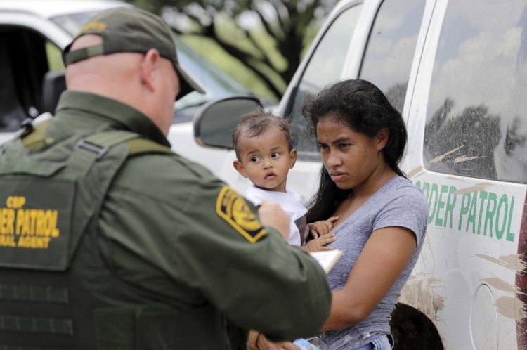 A mother migrating from Honduras holds her 1-year-old child as she surrenders to Border Patrol agents after illegally crossing into the U.S. in June 2018 near McAllen, Texas. The government said in a court filing Friday that it could need two years to identify all the children separated from their families at the border over the course of a year.