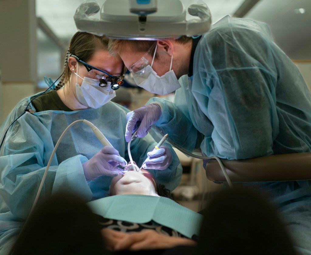 PORTLAND, ME - NOVEMBER 1: Stephanie Beeckel, left, and Chris Priest perform a dental cleaning for Mary Rena at the Oral Health Center at the University of New England in Portland on Friday, November 2, 2018. The university participated in the Dentists Who Care for ME on Friday, an event where dentists in Maine provide free dental care for people who can't afford regular dental care or who don't have insurance. Beeckel is a third year dental student and Priest a first year dental student at UNE. (Staff photo by Gregory Rec/Staff Photographer)