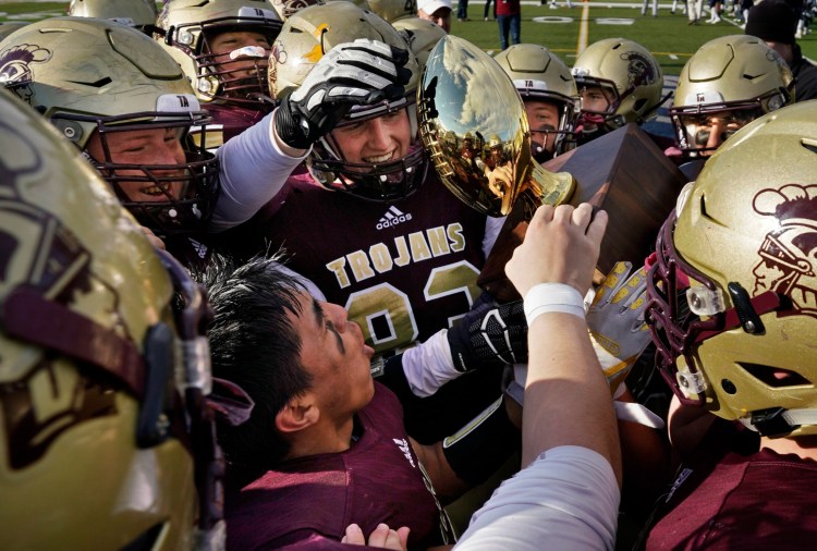 PORTLAND, ME - NOVEMBER 17: Ethan Logan, center and Anthony Bracamonte, below, and other Thornton Academy players hold the championship trophy while celebrating their 49-14 victory over Portland in the Class A Football state championship at Fitzpatrick Stadium in Portland on Saturday, November 17, 2018. (Staff photo by Gregory Rec/Staff Photographer)
