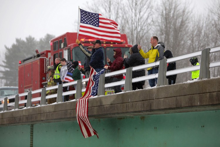 Representatives of the Richmond Fire Department and the Sagadahoc County Sheriff’s Office, local veterans, and residents stand on an Interstate 295 overpass in Richmond on Monday to honor Maine State Police detective Benjamin Campbell as the procession with his body makes its way to Portland for Tuesday’s funeral service. 