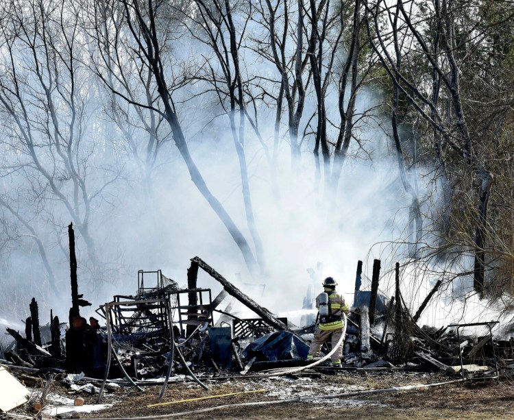 A firefighter sprays water on the burning remains of a barn at 658 Webber Pond Road in Vassalboro on Sunday.