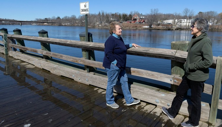Liane Slade, left, and Merrilee McMillin chat Thursday on the waterfront along the Kennebec River in Gardiner. Rain and warm weather are in the forecast for this weekend, raising the potential for flooding at the start of next week.