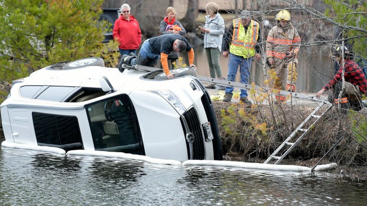 A Litchfield firefighter inspects a vehicle that overturned into Woodbury Pond on Monday in Litchfield.