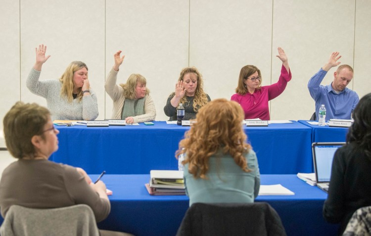 School Administrative District 49 board members – at rear from left, Katie Flood-Gerow, Kara Kugelmeyer, Katrina Dumont, Jenny Boyden and Shawn Knox – vote with six other board members to put out to bid a request for proposal for legal counsel during an April 11 school board meeting at Lawrence junior High School in Fairfield.