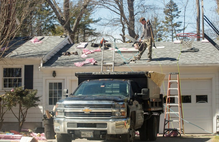 A crew from Purvis Home Improvement works on the roof of a home in Cape Elizabeth on Thursday. The owner of the Scarborough home improvement company, Shawn D. Purvis, faces manslaughter charges in the death of a roofer who fell from a roof on Munjoy Hill in Portland in December.