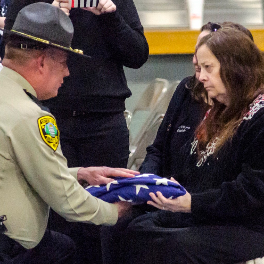Kennebec County Sheriff Ken Mason, left, hands Rhea Williams the flag from the casket of her late husband, Donald Williams, at the end of Williams' funeral Saturday at the Maine Criminal Justice Academy in Vassalboro. 