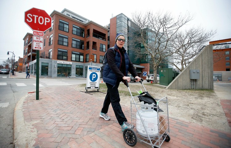 Peaks Island resident Molly Johnson pushes a cart last week from the Ocean Gateway Garage, where she has a monthly parking pass. Garage manager Unified Parking Partners had told some island residents last week that they would be evicted from their spaces, but said Friday that at least some of the residents would be allowed to keep their spaces.