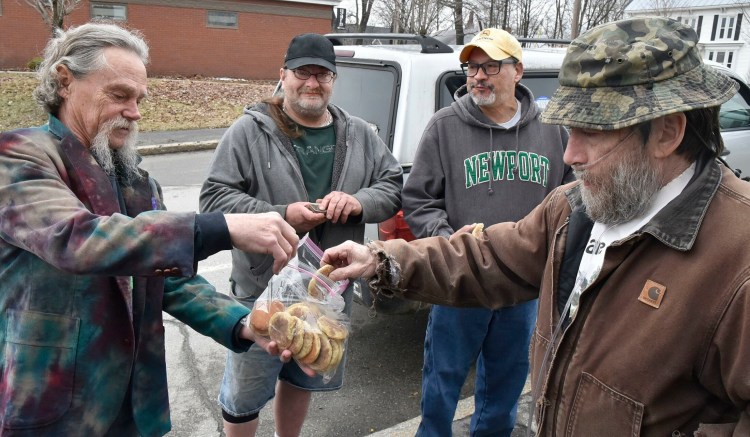 Marijuana advocate Donny Christen, right, accepts a cookie made with pot from Robert Hardenburg, left, outside the Somerset County Courthouse in Skowhegan during the annual Patriot's Day "smoke in" on Monday. Participating in the event were Joey Annaloro, second from left, and Pedro Quintela.