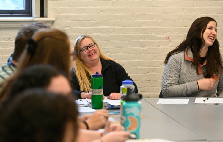 Lisa Bouffard shares a laugh with fellow students during a Christianity class at Bowdoin College in late April. After 18 years of taking one class per semester. Bouffard, who also works in the college's dining services  department, will graduate. 