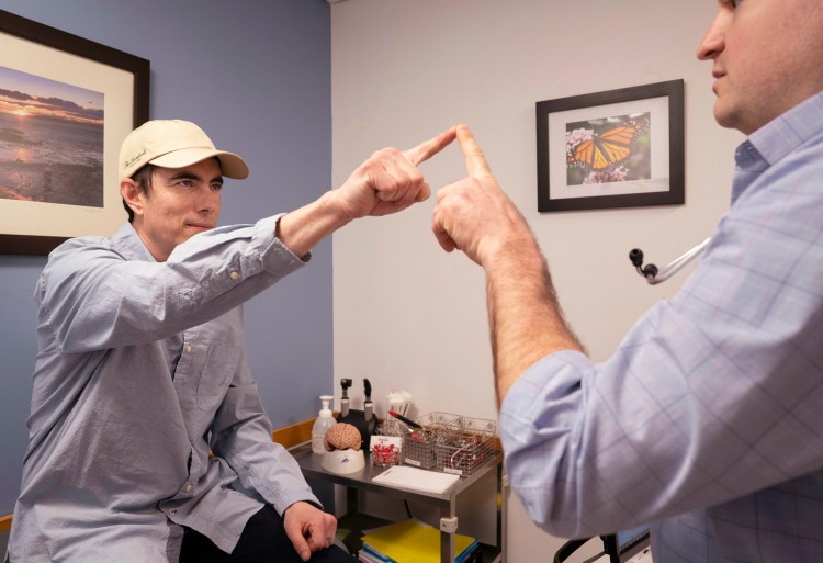 Gregory Francis touches the finger of physician assistant Sam Gagnon during a neurological examination at Maine Medical Partners in Scarborough on April 18. Francis had a brain tumor removed and is on medication prescribed based on a biopsy of the tumor done by Jackson Laboratory.