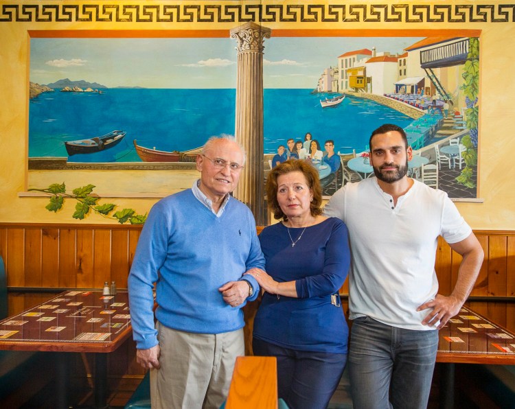 Owners of the Falmouth House of Pizza, Sotirios, Antonia and Lee Soritopoullos, stand in the dining area of their restaurant.
