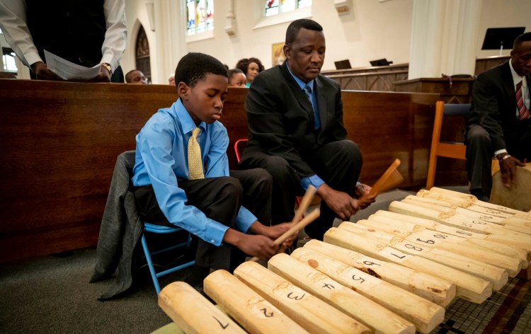 Victor Tartizio, 13, and his father, Dennis, play the ngbaningbo Sunday during an Azande Mass for members of Greater Portland's Sudanese community at the Cathedral of the Immaculate Conception in Portland.