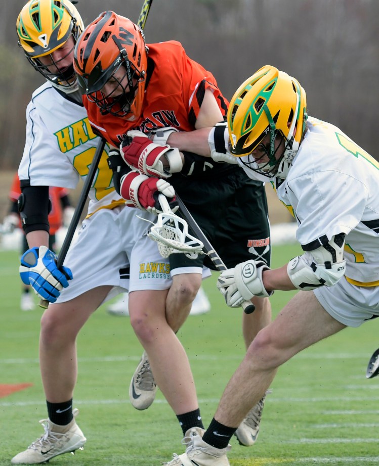Maranacook/Winthrop/Spruce Mountain teammates Will Colvin, left, and Jacob Sousa sandwich Winslow's Jared Lambert during a lacrosse game Monday at Kents Hill School.