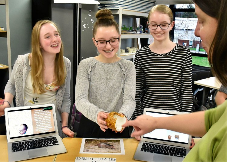 Brynn Lilly, from left, Isabelle L'Italien and Lily Mitchell, students with the gifted and talented program at Messalonskee Middle School, show Brigid Mullally a human infant skull cap made with a 3-D printer that replicates armadillo armor during a biomimicry project at Thomas College in Waterville on Tuesday.