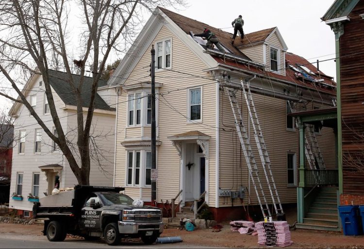 Workers from Purvis Home Improvements of Scarborough were back on the job at a home on Munjoy Hill in Portland the day after a worker died in a fall from the roof in December 2018. 