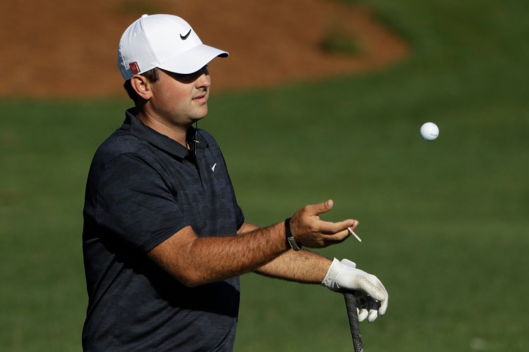 Patrick Reed gets a ball from his caddie at the practice area for the Masters golf tournament Wednesday, April 10, 2019, in Augusta, Ga. (AP Photo/Marcio Jose Sanchez)