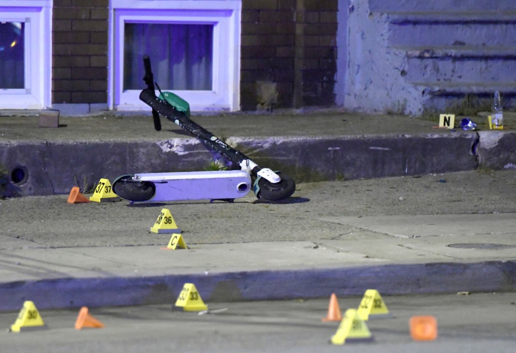 A scooter lies among evidence markers near the scene where authorities say seven people were shot, at least one fatally, Sunday, April 28, 2019, in Baltimore. (AP Photo/Steve Ruark)