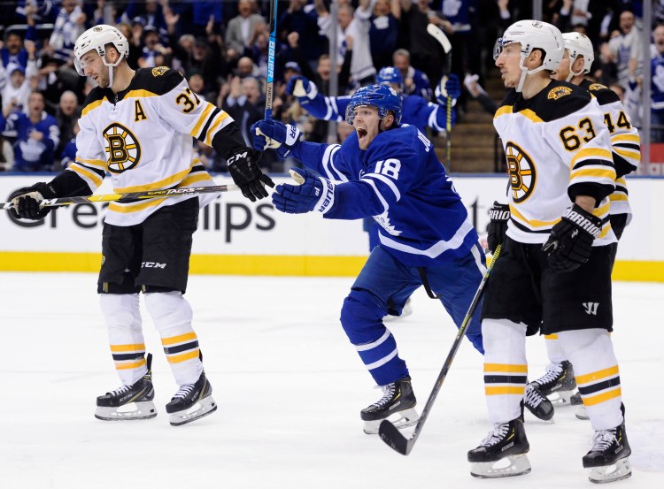 Toronto Maple Leafs left wing Andreas Johnsson (18) celebrates his goal as Boston Bruins center Patrice Bergeron (37) and left wing Brad Marchand (63) look on during second-period NHL playoff hockey action in Toronto, Monday, April 15, 2019. (Nathan Denette/The Canadian Press via AP)
