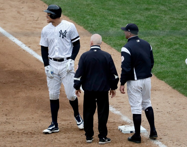 With the Yankees’ trainer and bench coach Josh Bard checking on him, Aaron Judge reacts Saturday to what proved to be a strained oblique muscle after singling against Kansas City.