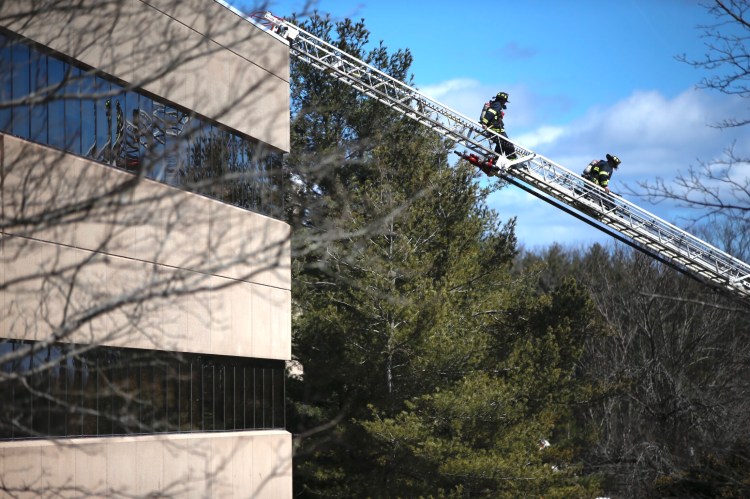 Firefighters descend a ladder from the roof of the Unum office building at 2211 Congress St. in Portland on Saturday after extinguishing a fire there. 