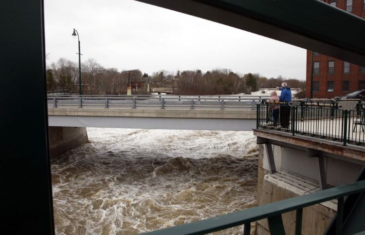 The Presumpscot River rages under Bridge Street on Saturday while Portland residents Mary DeLois and Bob Raff observe the scene. 