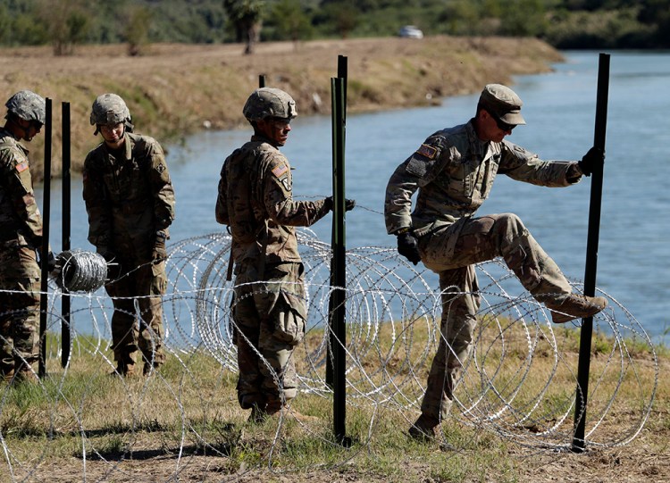 Members of the U.S. military install multiple tiers of concertina wire along the banks of the Rio Grande in Laredo, Texas at the U.S.-Mexico border in 2018.