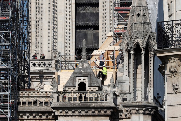 Workers stand by wooden planks supporting Notre Dame cathedral on Friday.