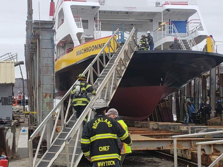 Rockland firefighters haul hoses up to the deck of a ferry at Rockland Marine.