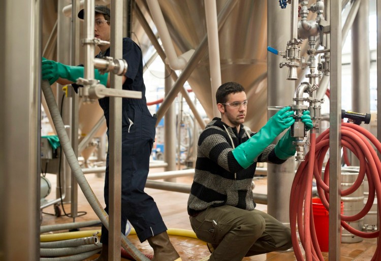 David Love, right, and Phil Neil work in the brewery at Maine Beer Co. in February. The company announced a plan Thursday to help increase renewable energy across the state. 