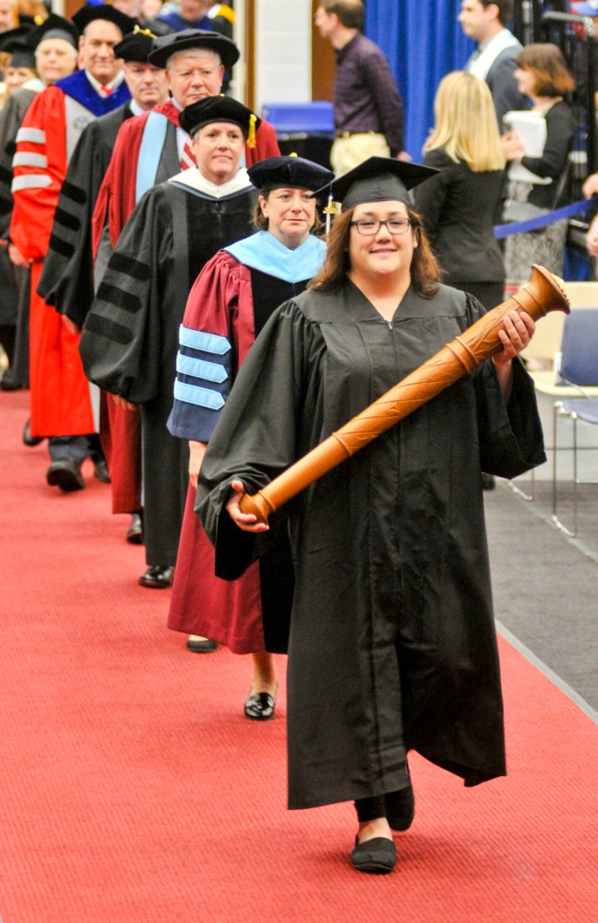 Jacquelyn Estrella carries the mace and leads the procession Saturday at the beginning of the University of Maine at Augusta commencement at the Augusta Civic Center.