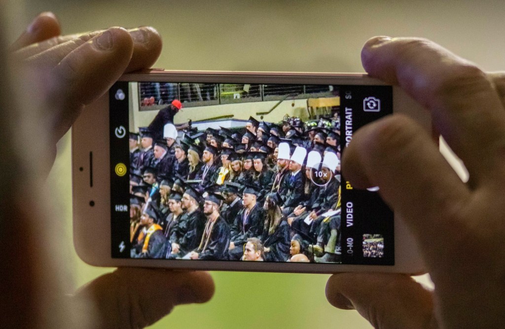 PORTLAND, ME - MAY 12:  An attendant at the Southern Maine Community College commencement, at Cross Insurance Arena in Portland, enlarges a phone photo to get a better look at the graduate they were there to support on Sunday, May 12, 2019.(Staff Photo by Carl D. Walsh/Staff Photographer)