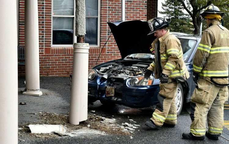 Waterville firefighters inspect damage to the entryway support columns Wednesday at Mount Saint Joseph Nursing Home in Waterville after the car in the background struck one of the columns.