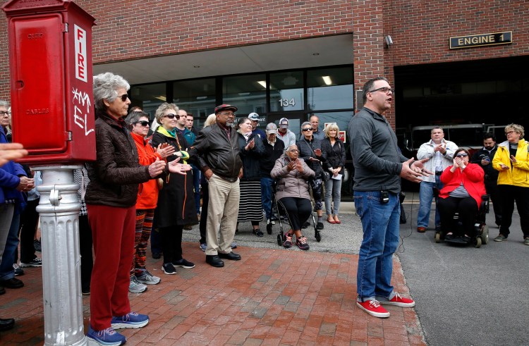 State Rep. Mike Sylvester, whose district includes Munjoy Hill, is flanked by about 30 people outside the neighborhood's fire station Friday to protest a city budget proposal that would decommission the station's Engine 1 and reassign its crew.