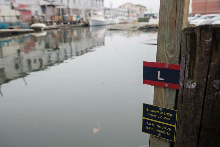 A plaque shows the low-end estimate for water level in 2050 on Portland Pier in the event of a storm like the "Blizzard of 1978." Sea-level resilience strategies are on Maine's to-do list. 