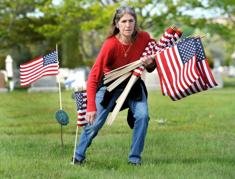 SOUTH PORTLAND, MAINE - MAY 22, 2019:   
VFW club members and volunteers place small American flag's on the grave sites of veterans at the Forest City cemetary in South Portland. Paula Hollenkamp, vice president at the women's auxilary at Portland's VFW Post 161, places American flags on veterans graves. ( Photo by John Ewing/Staff Photographer)