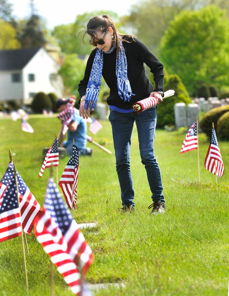SOUTH PORTLAND, MAINE - MAY 22, 2019:   
VFW club members and volunteers place small American flag's on the grave sites of veterans at the Forest City cemetary in South Portland. Suz (cq) Lamb, from Westbrook, helped VFW members place amerian flags on the graves of veterans. ( Photo by John Ewing/Staff Photographer)