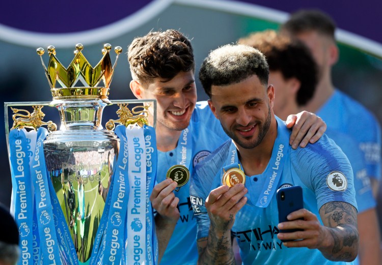 Kyle Walker, right, and John Stones of Manchester City take a selfie with their medals and the English Premier League trophy Sunday after a clinching win.