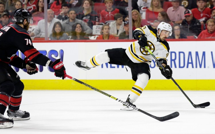 Boston Bruins' Brad Marchand (63) takes a shot on goal while Carolina Hurricanes' Jaccob Slavin (74) defends during the first period in Game 4 of the NHL hockey Stanley Cup Eastern Conference final series in Raleigh, N.C., Thursday, May 16, 2019. (AP Photo/Gerry Broome)