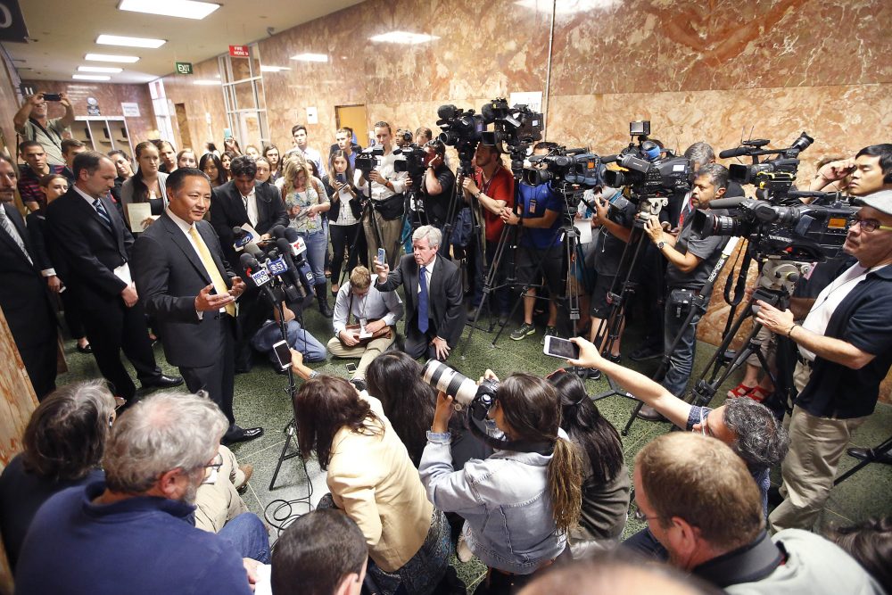 FILE - In this July 7, 2015, file photo, San Francisco Public Defender Jeff Adachi, left, talks to members of the media after Francisco Sanchez' arraignment in San Francisco. A freelance journalist is vowing to protect his source after San Francisco police raided his home and office as part of a criminal investigation. Bryan Carmody tells the Los Angeles Times that officers handcuffed him Friday, May 10, 2019, as they confiscated items including his cell phone, computer and cameras. Authorities say the raid came during an ongoing probe into who leaked a confidential police report about the Feb. 22 death Adachi. (AP Photo/Tony Avelar, File)