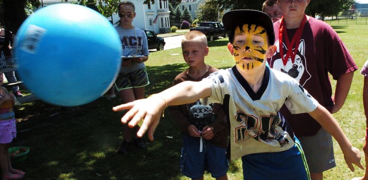 After getting his face painted as a tiger Joshua Stineford  tosses a ball into a bucket during Egg-Olympics activities of the Central Maine Egg Festival in Pittsfield on July 13, 2016. 