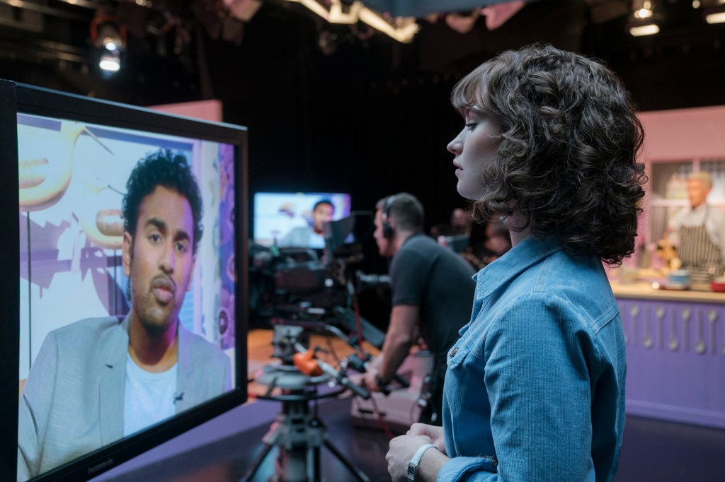 Himesh Patel, left on TV screen, and Lily James star in "Yesterday." MUST CREDIT: Jonathan Prime, Universal Pictures