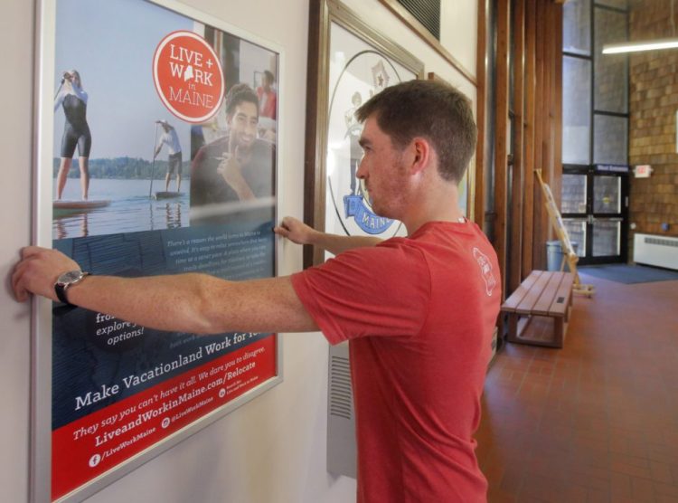 Nate Wildes of Live and Work in Maine sets up a poster at the Kittery information center in 2016.