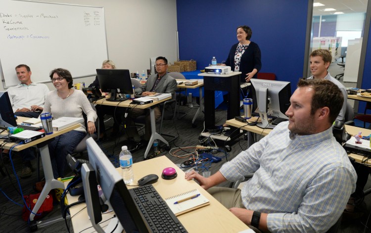 Training and development manager Amy Kavanaugh, back center, leads a training group for Portland-based BlueTarp Financial. On Friday the company announced it is being purchased by Capital One.