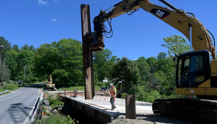 A Wyman and Simpson worker guides a pier into place to support the temporary bridge spanning the headwaters of Echo Lake in Mt. Vernon in June. The Richmond construction company is replacing the old bridge on Route 41 for the Maine Department of Transportation. The DOT is hoping $105 million in bonds will get legislative backing before the end of the month so they can go on November ballots. If passed, the bonds would provide money for next year's transportation projects.