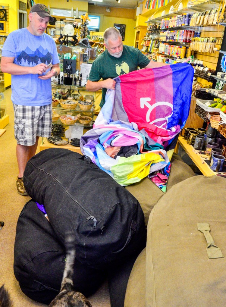 Bishop McKechnie, left, and David Hopkins talk about the River of Pride flag Thursday at their shop, Merkaba Sol, in downtown Augusta. The duffel bags hold sections of the 22-by-1,650-foot-long River of Pride rainbow flag. McKechnie started out making a shorter version of the rainbow flag for the Portland Pride parade in 2006. They've been invited to bring both the River of Pride and, his newest creation — the 20-feet by 200-feet Unity Flag, made up of smaller 3-feet by 5-feet flags — to the New York City Pride parade on Sunday. 