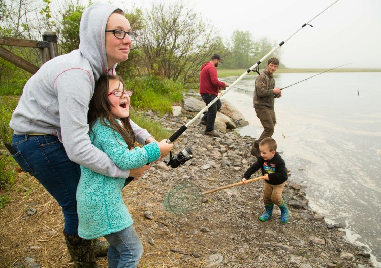 Ariana Stinchfield helps her excited daughter, Bailey Dubois, 6, fish in the Spurwink River in Scarborough on Sunday. The Freedom, N.H., family, including Ariana’s husband, Dylan Dubois, left, brother Kenneth Stinchfield of Parsonsfield and son Bryden Dubois, 3, got to fish without a license Sunday as part of the annual Maine Department of Inland Fisheries and Wildlife special weekend.