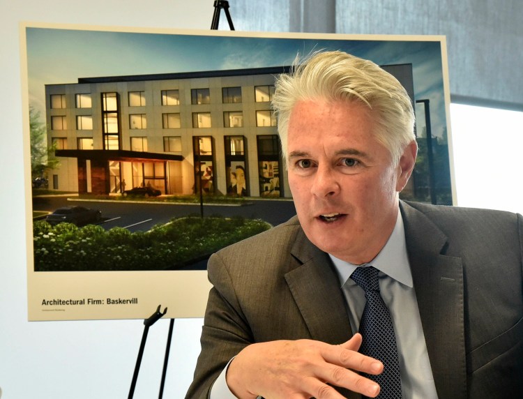 Speaking before an architect’s rendering of The Lockwood Hotel, David Greene, president of Colby College, on June 3 outlines plans for the hotel that will be built in downtown Waterville.