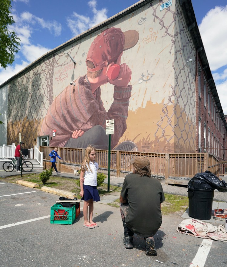 Artist Pat Perry talks with Rhys Cote on Tuesday about the mural he painted on the side of a building in Biddeford. The mural is paired with a similar mural that Perry painted in Iraq. Rhys is a fourth-grade student at St. James School in Biddeford and came by with her mother to see the mural.
