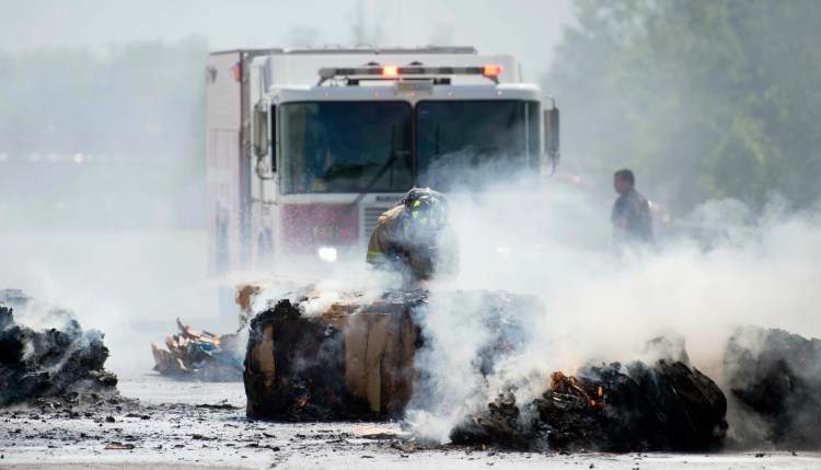 Bundles of recycled cardboard burn Saturday behind Walmart in Waterville as firefighters work to extinguish it.